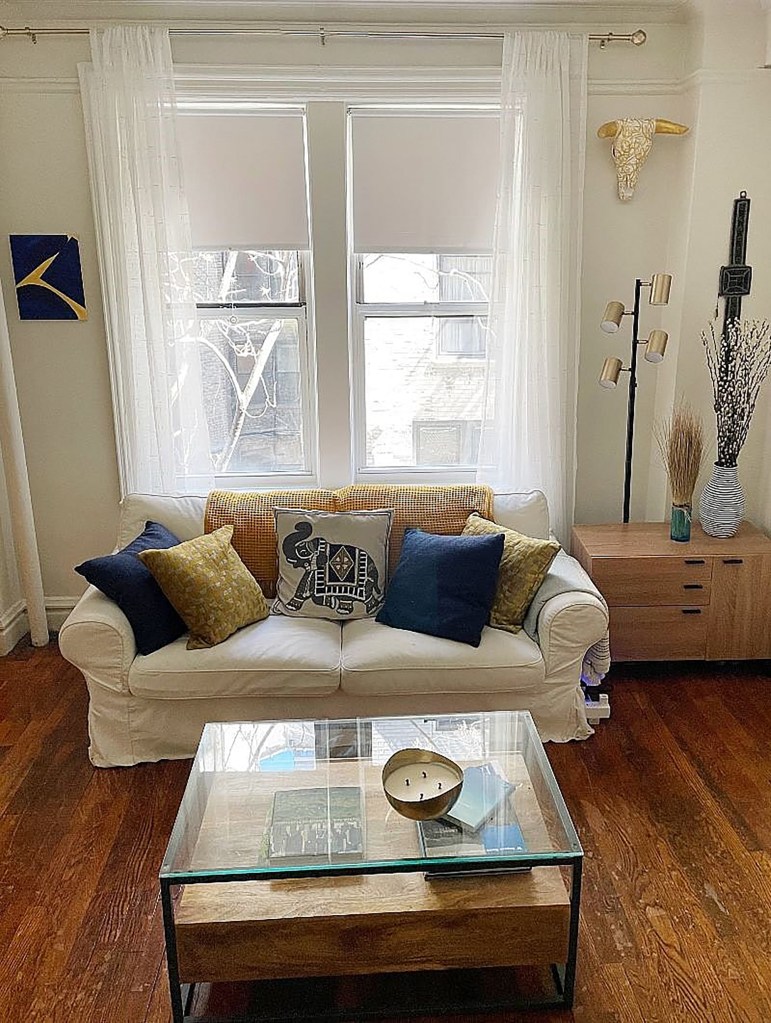 A furnished studio apartment with a couch and glass coffee table in the living room, located in the Upper West Side of New York City