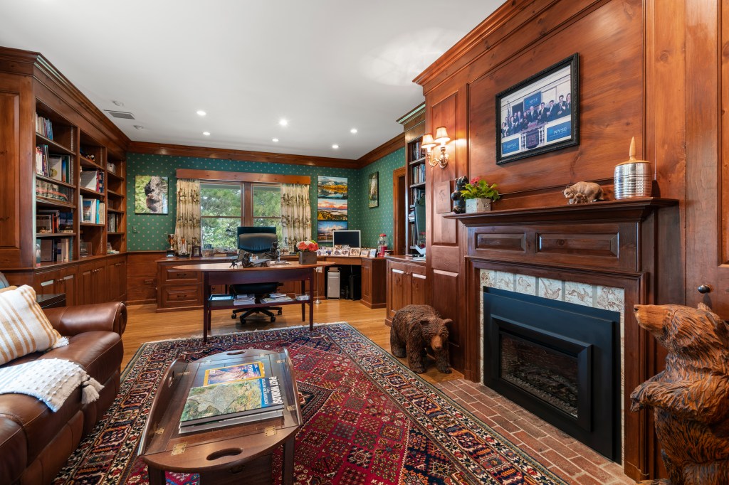 A fireplace, wood-paneled walls and jewel-tone paint adorn this home office.