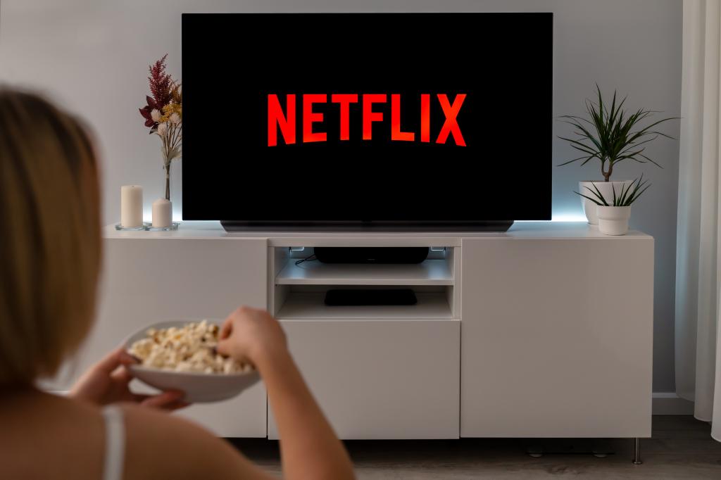 Netflix logo on TV screen with woman eating popcorn.