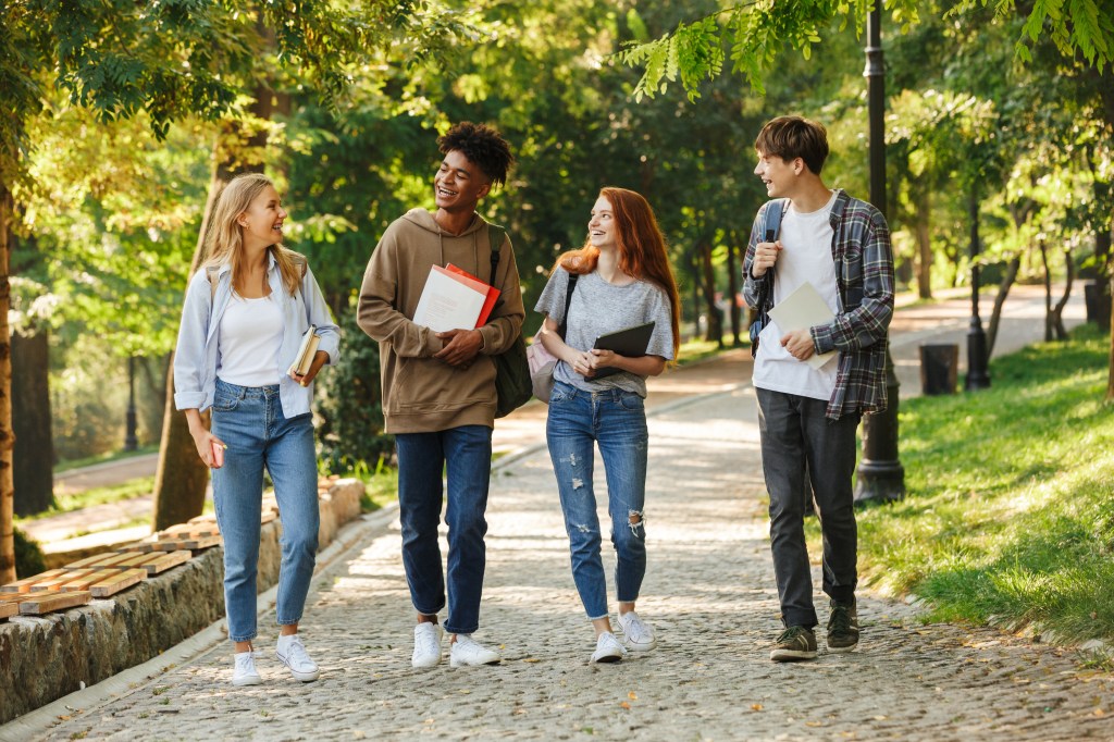 Group of happy students walking at the campus outdoors