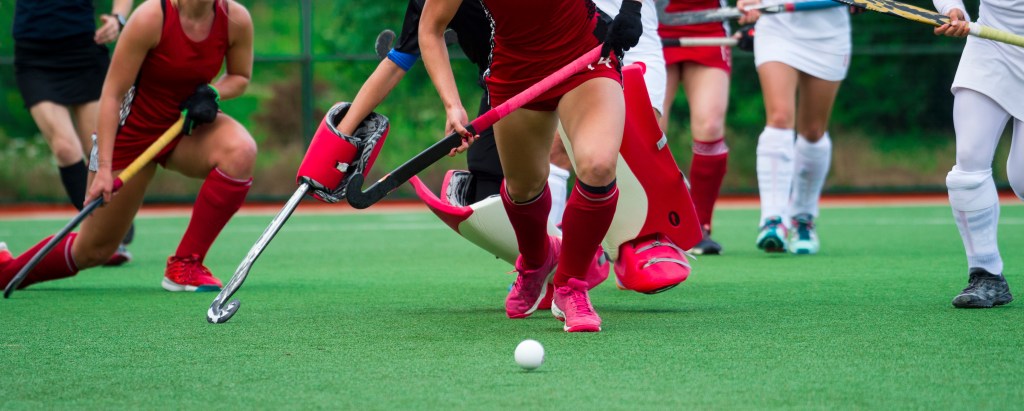 Field hockey players challenging each other for ball possession during a midfield battle in a match