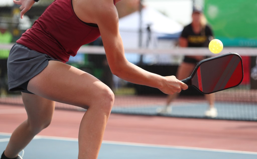 A woman playing pickleball, returning a volley