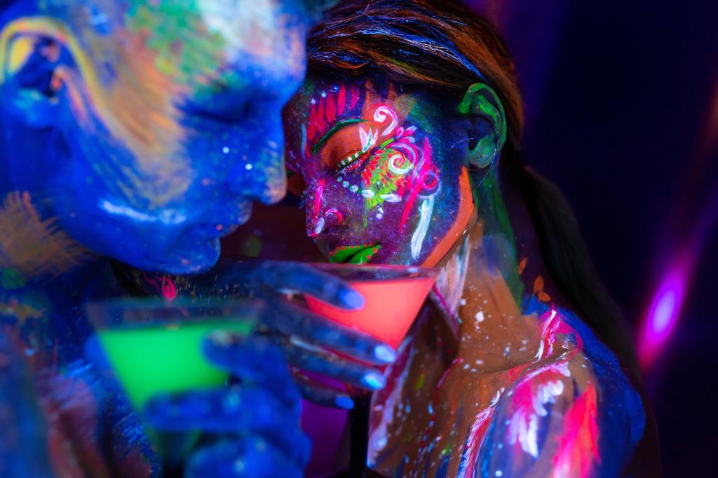 Young couple with fluorescent bodyart drinking alcoholic drinks in a nightclub