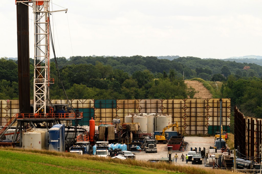 A fracking well in front of a moutainous background