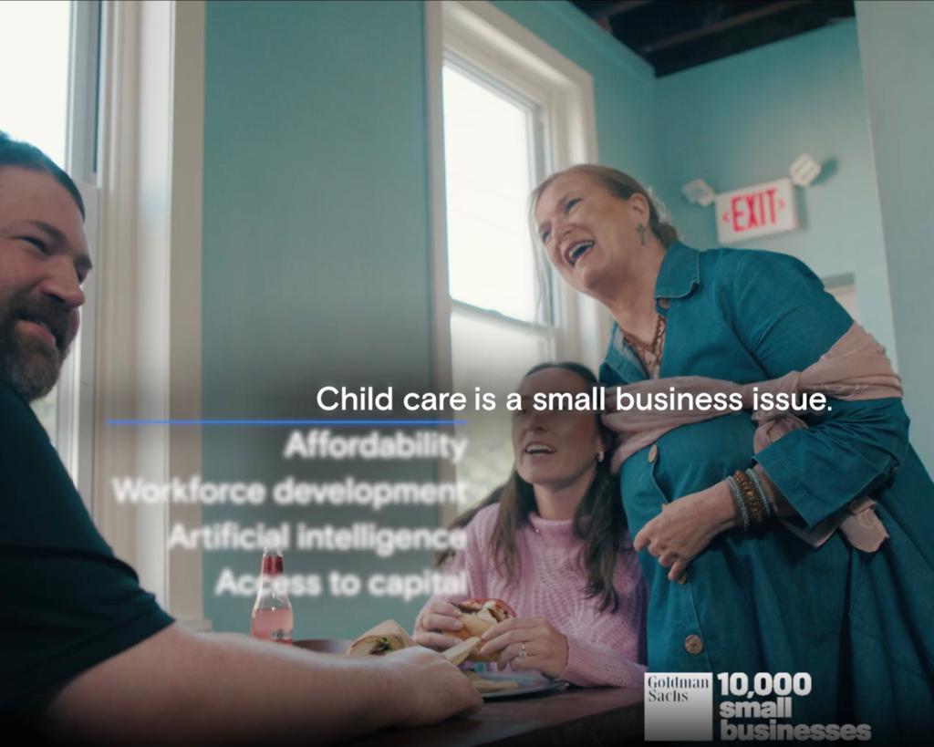 Jenny Owens and a group of people laughing at a table in a Goldman Sachs small business advertisement