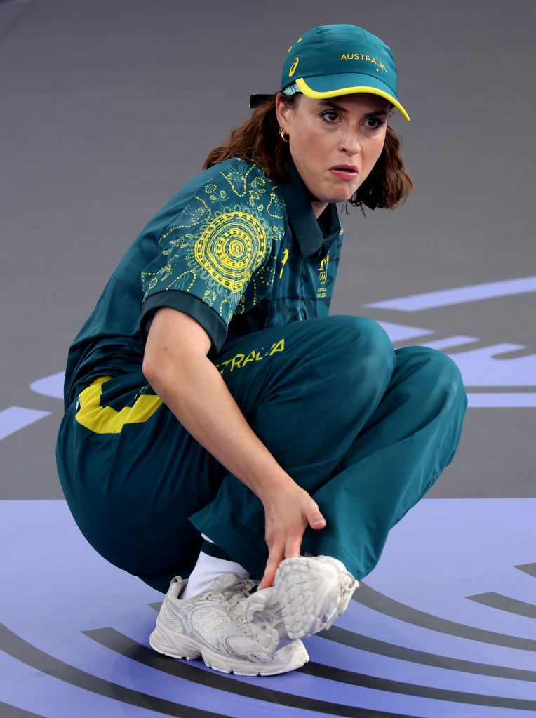 B-Girl Raygun of Team Australia competing in the Round Robin Group B event during the Olympic Games Paris 2024, squatting on a blue mat in a green and yellow outfit