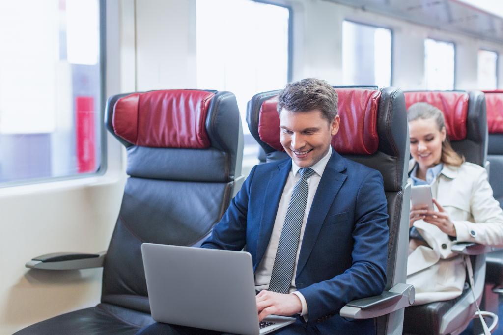 Young businessman in a suit and tie using a laptop on a train