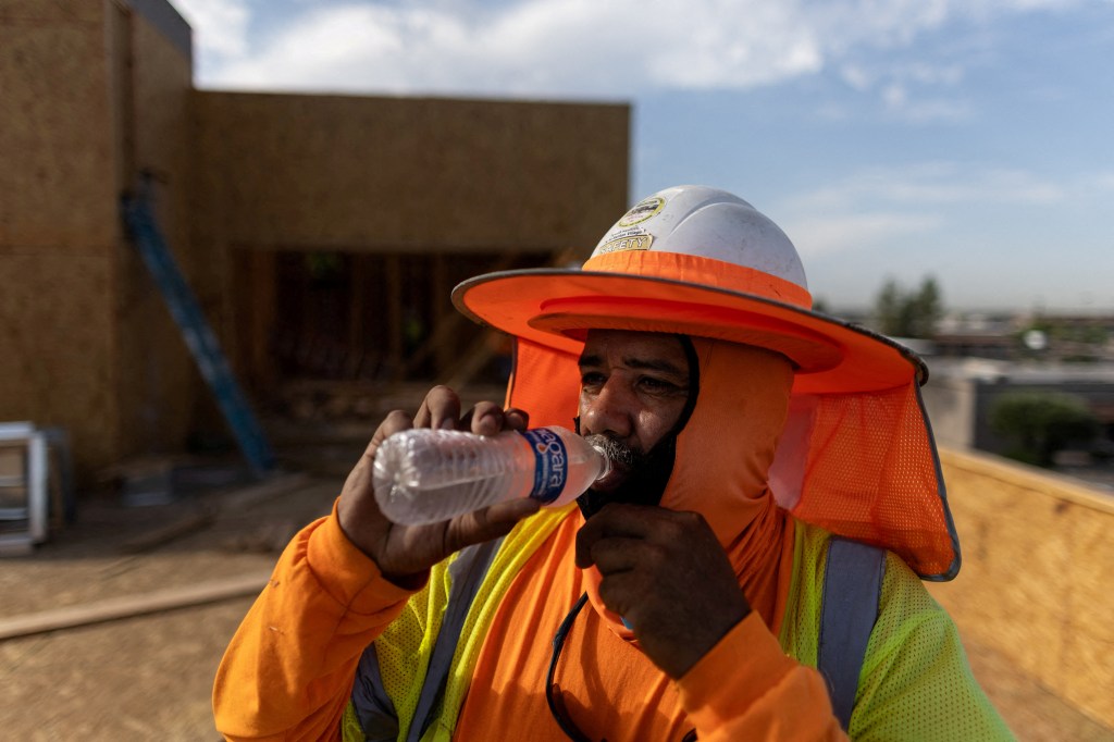 A construction worker drinks cold water during a heat wave where temperatures rise over 110 degrees Fahrenheit for 27 consecutive days, in Scottsdale, at the Phoenix metro area