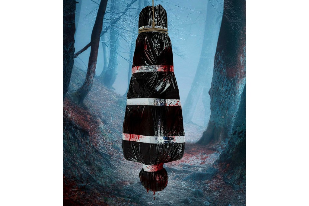 Black bag with blood hanging from a rope in a forest