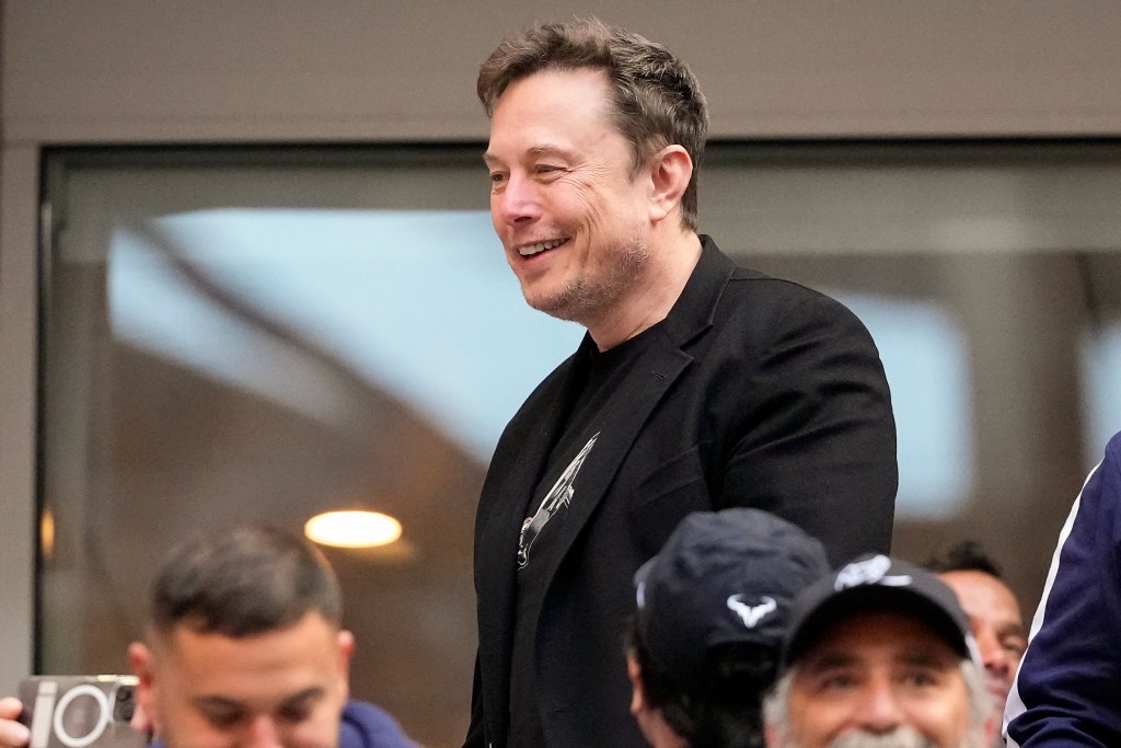 Elon Musk talks to other spectators while watching play between Jannik Sinner, of Italy, and Taylor Fritz, of the United States, during the men's singles final of the U.S. Open tennis championships, Sunday, Sept. 8, 2024.