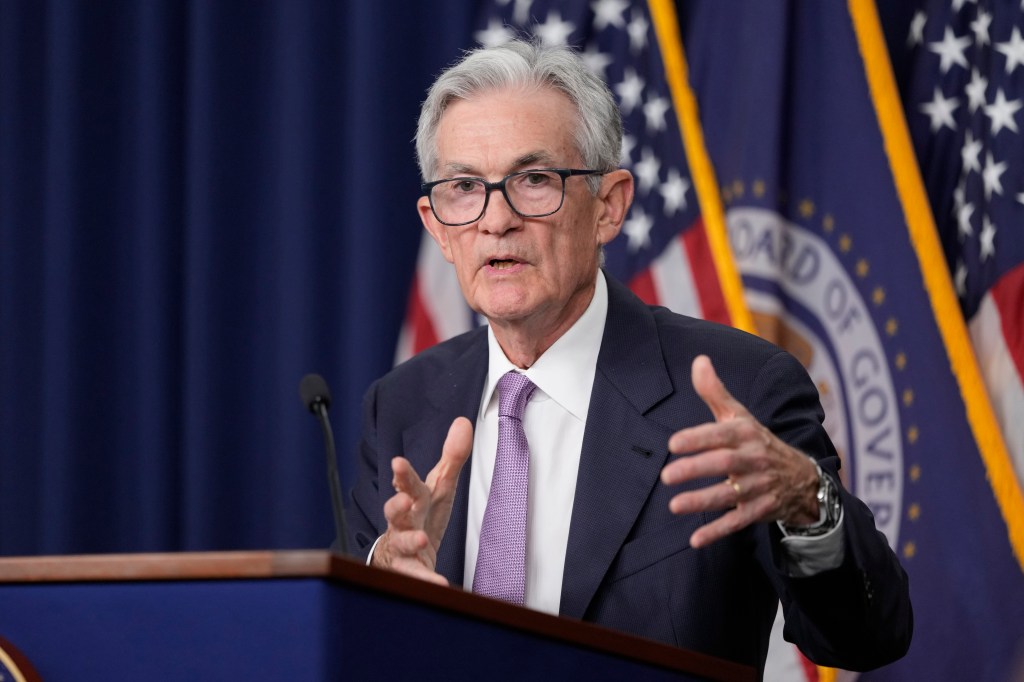 Federal Reserve Board Chairman Jerome Powell speaking at a news conference about reducing interest rates, gesturing at the podium