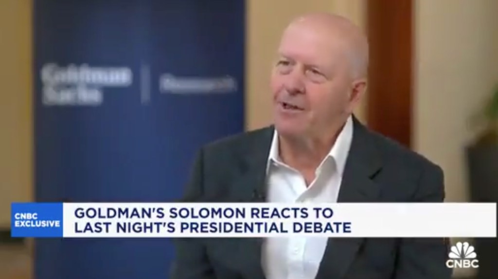 Goldman Sachs CEO David Solomon in a suit discussing a report related to Vice President Kamala Harris.