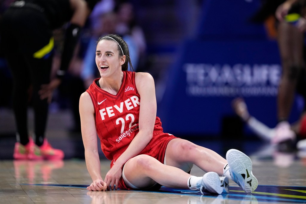 Indiana Fever guard Caitlin Clark smiling and looking towards the team bench after making a successful pass during a WNBA game