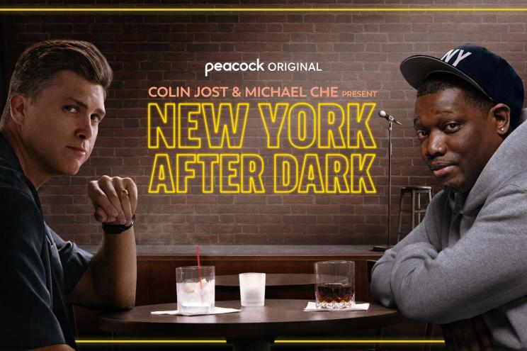 Michael Che and Colin Jost sitting at a table