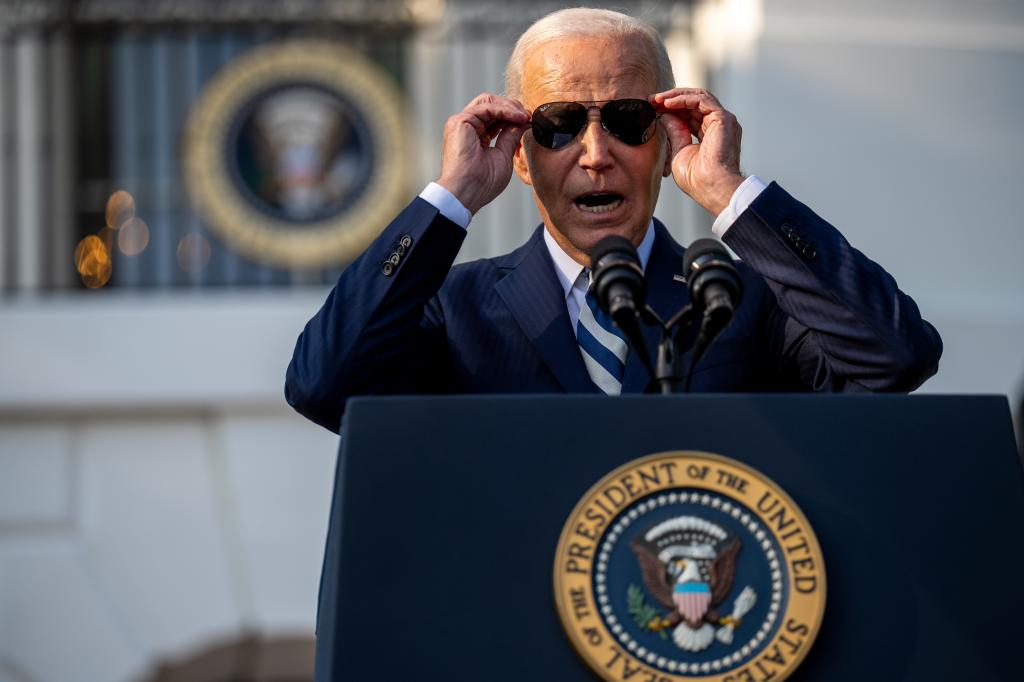 President Biden puts on his sunglasses in front of a Washington crowd.