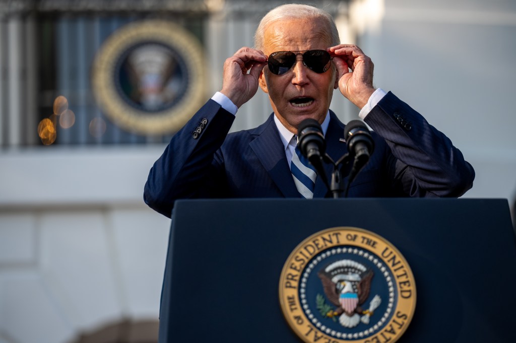 President Biden puts on his sunglasses in front of a Washington crowd.