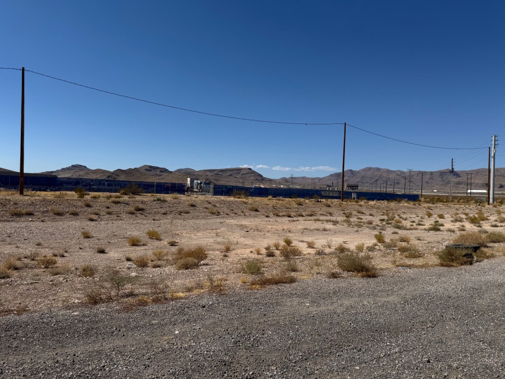 Empty lot in North Las Vegas, Nevada with power lines and mountains in the background, previously the location of a hoisted nude statue of Donald Trump