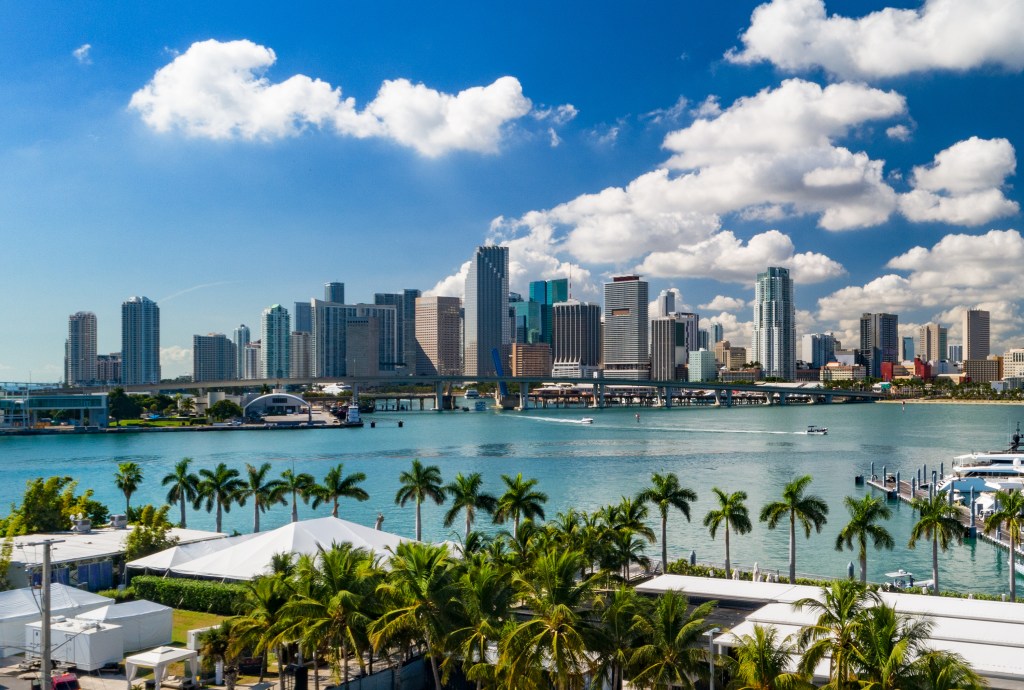 Downtown Miami skyline viewed from a low elevation, featuring palm trees and Biscayne Bay in the foreground, representing post-pandemic housing market changes in South Florida.