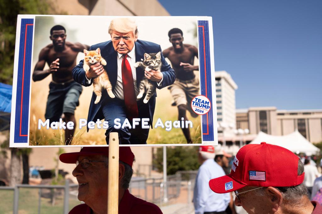 A man carries an AI-generated image of former US President and Republican presidential candidate Donald Trump carrying cats away from Haitian immigrants.