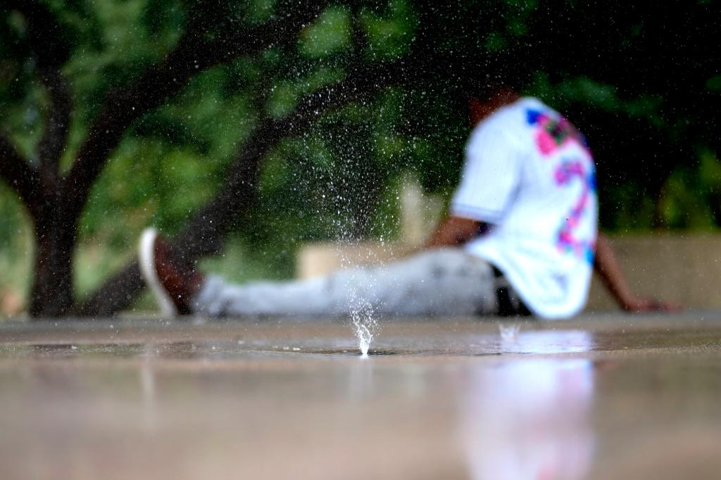 A man attempting to keep cool in a splash pad in Phoenix on June 25, 2024.