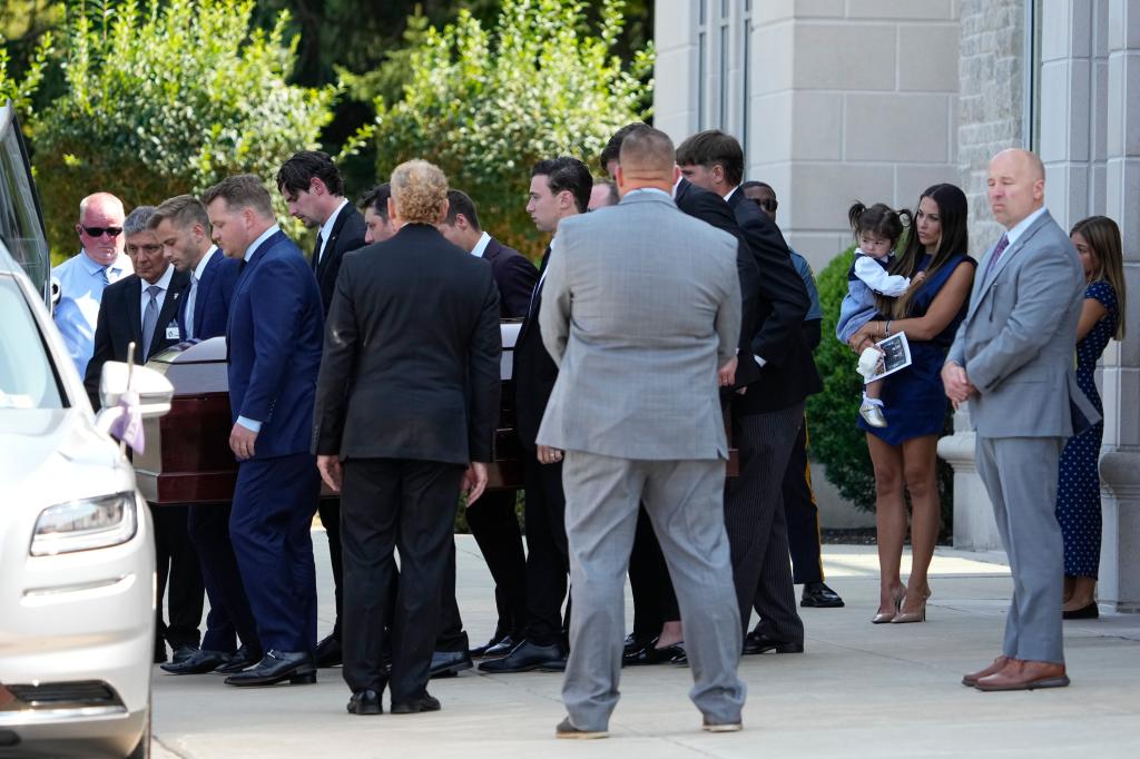 Meredith Gaudreau (in blue) watches with her daughter, Noa, as pall bearers carry out the caskets of her husband Johnny, and his brother Matthew following the funeral at St. Mary Magdalen Parish.