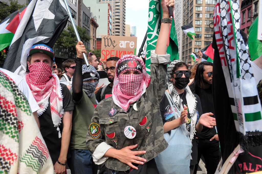 Pro-Palestine demonstrators waving flags during a rally in Manhattan, New York City, with Shikha Uberoi present among the crowd.