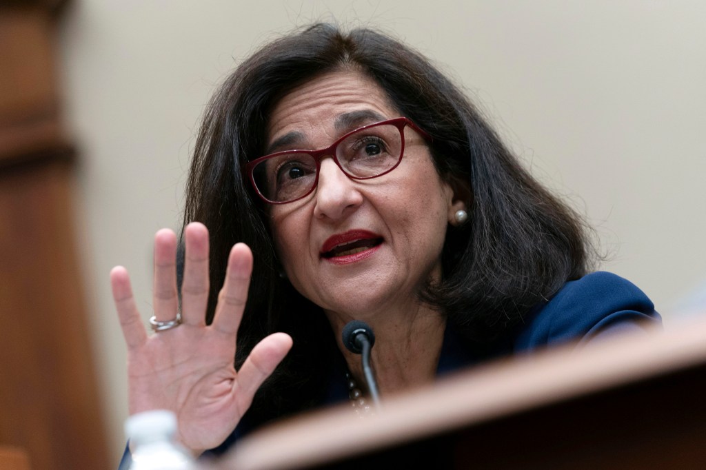 Manouche Shafik speaking into a microphone and raising her hand