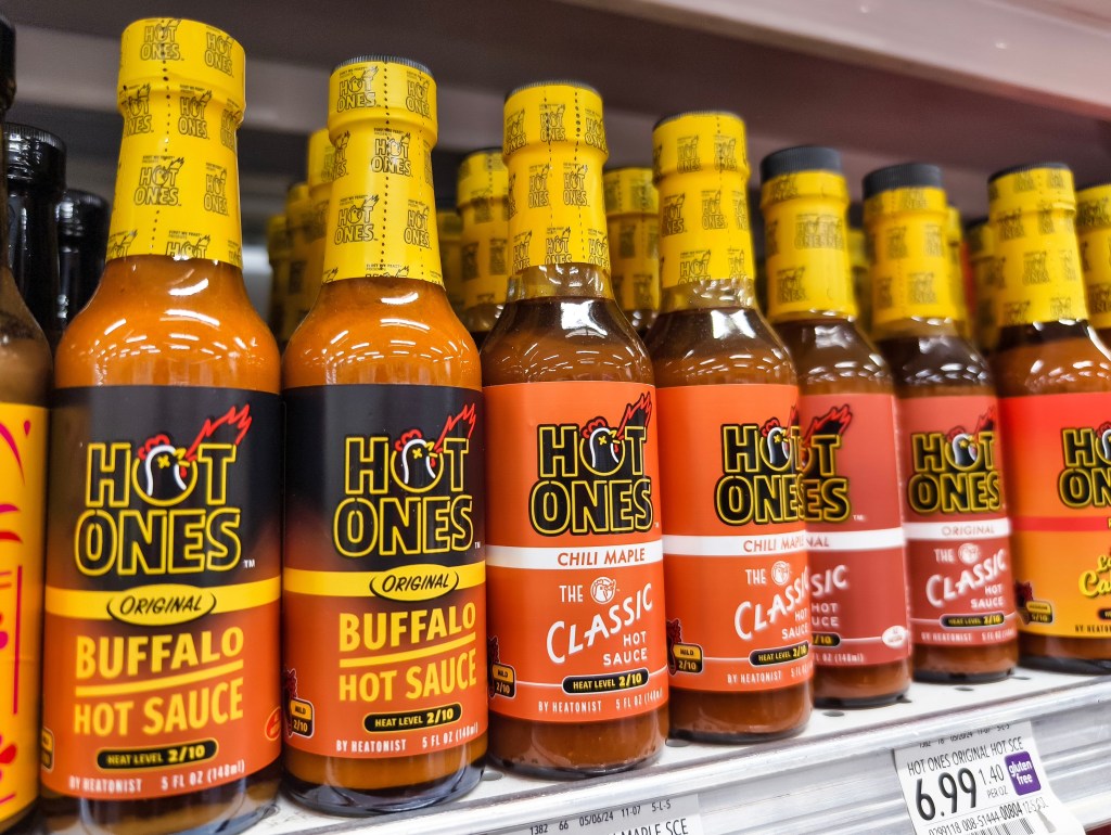 A row of hot sauce bottles on a shelf.