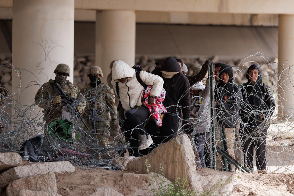 Texas National Guard soldiers in El Paso pushing back a group of migrants who crossed the border illegally by a wire barrier installed by Abbott on March 26, 2024.