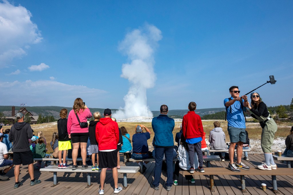 Tourists gathering on a boardwalk in Yellowstone National Park, Wyoming to watch the eruption of Old Faithful geyser on August 10, 2024.