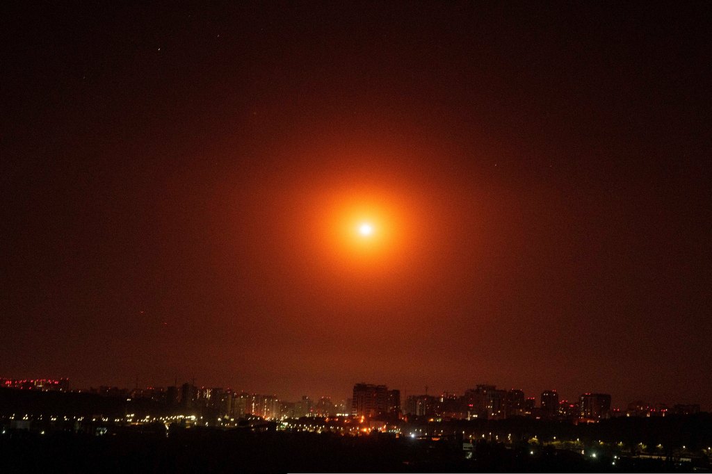 Ukrainian service personnel using searchlights to search for drones in the sky over Kyiv during a Russian drone strike.