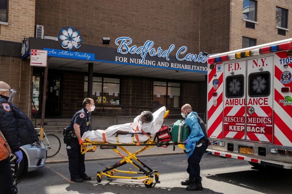 FDNY EMTs wearing protective equipment lifting a man from a nursing home into an ambulance during the COVID-19 outbreak in Brooklyn, New York