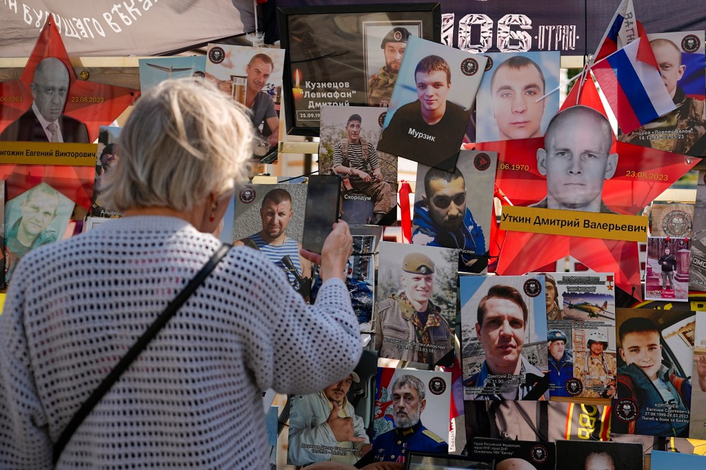 A woman takes pictures of portraits of Wagner's commander Dmitry Utkin and Wagner mercenary chief Yevgeny Prigozhin who died in a plane crash one year ago.