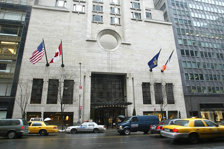 Exterior view of the Four Season Hotel located at 57 East 57th Street in Manhattan, featuring cars and flags in front.