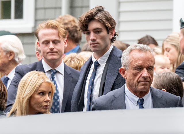 Cheryl Hines, Robert F. Kennedy Jr., and Aidan Caohman Vieques Kennedy attending the funeral for Ethel Skakel Kennedy in suits at Our Lady of Victory, Centerville, MA