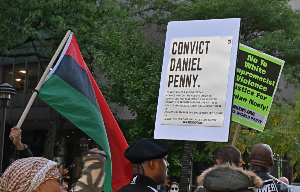 A demonstrator with a sign calling for Penny to be convicted.