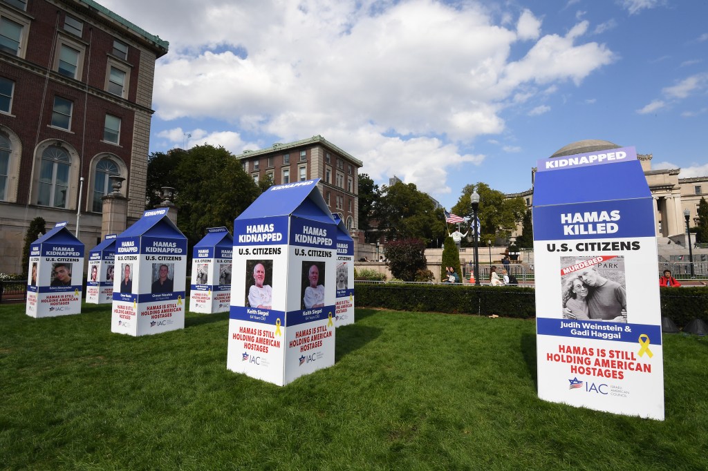 Memorial installation at Columbia University featuring white and blue tents with images, commemorating the one year anniversary of the attacks in Israel