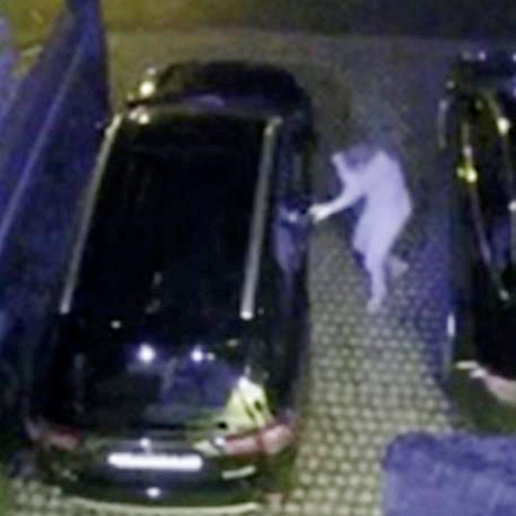 A person in a white suit reaching out of a car, indicative of a keyless car theft taking place in North London