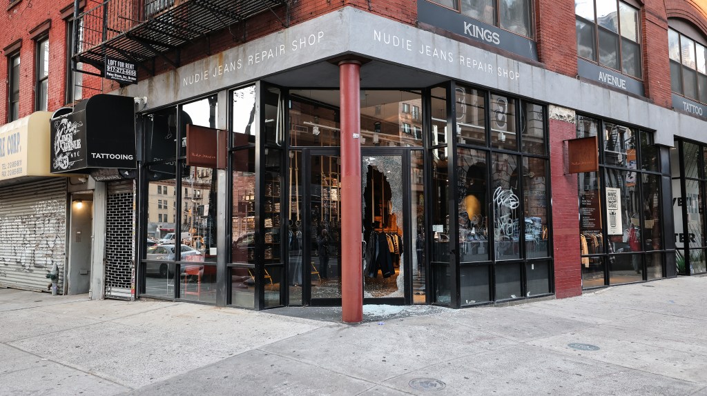 A photo of the front door of the Nudie Jeans Repair Shop in Soho, showing the gaping hole created when thieves used a fire hydrant cap to smash the glass. 