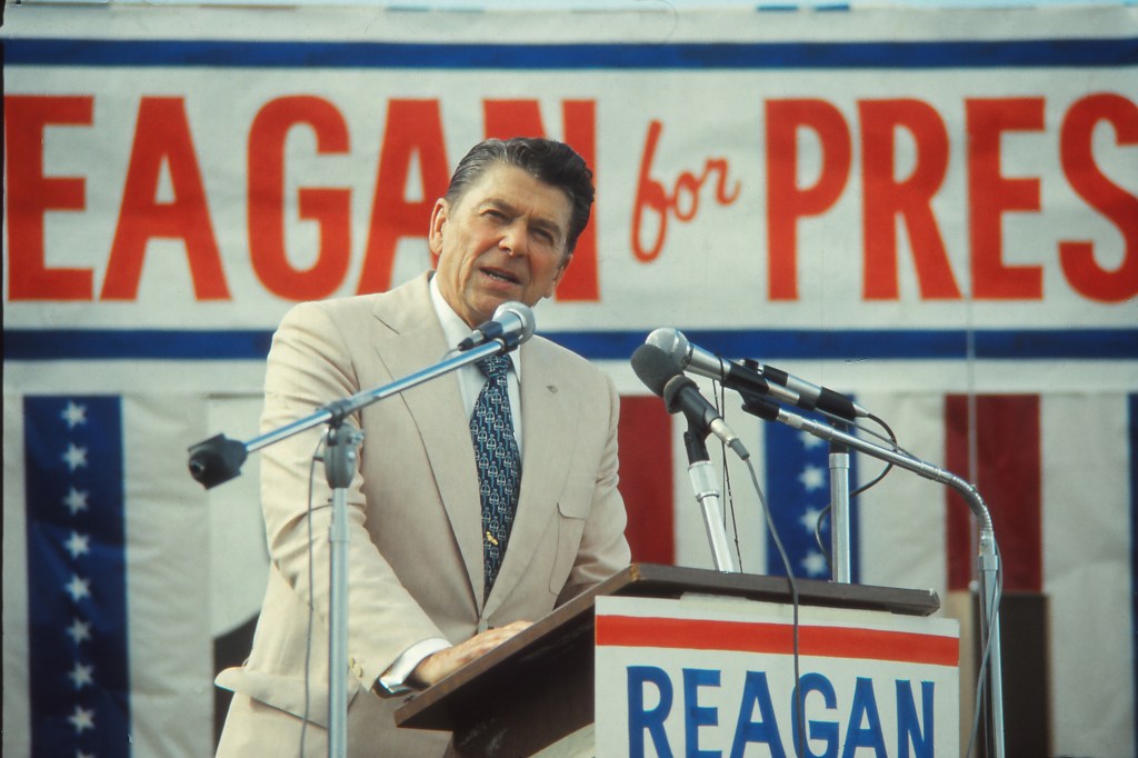 Ronald Reagan standing at a podium, speaking to an audience during his 1976 presidential campaign in Indiana