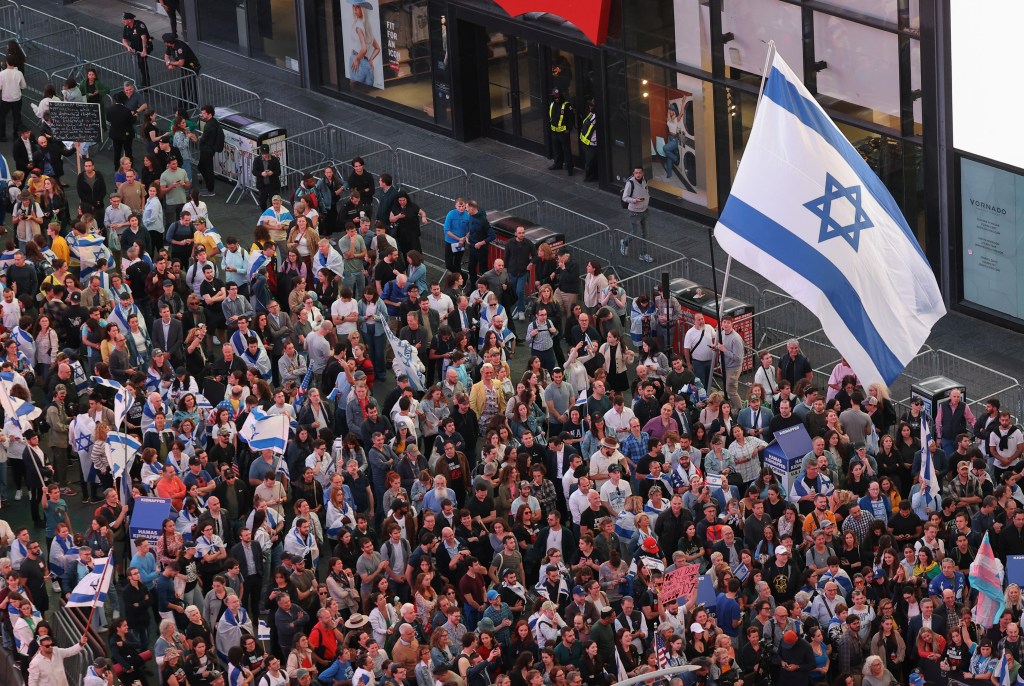 Large crowd gathering in Times Square, New York City, to commemorate the October 7, 2023 Israel attack, with people including Mrunalini Kunte and Ole Schröder present.