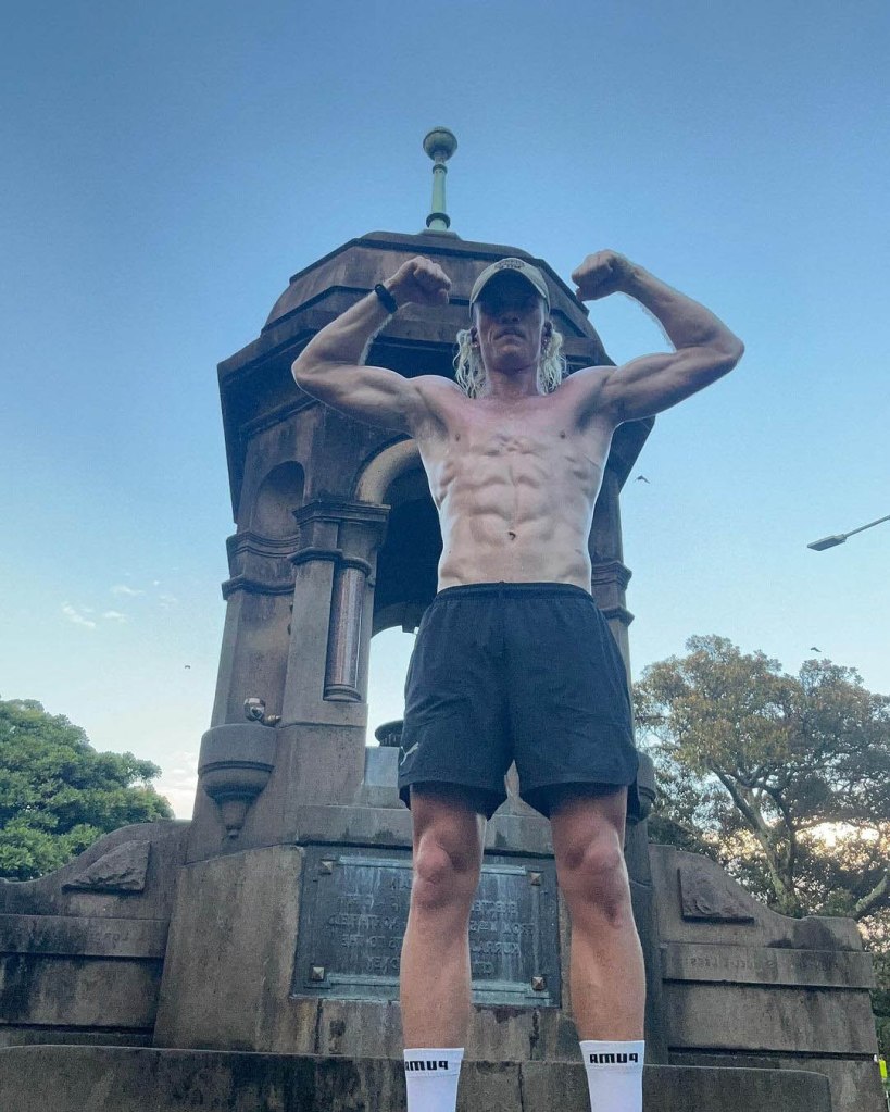 Nedd Brockmann pausing during his run and flexing his muscles in front of a building on a 7 degree day