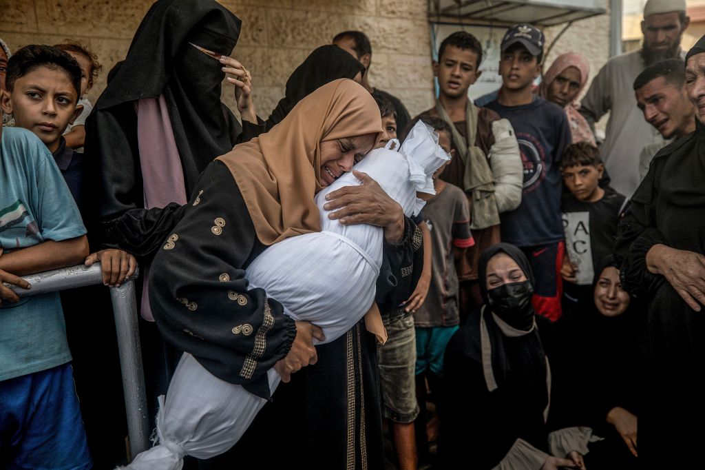 A woman holds a body following an Israeli air strike in Al Nusairat refugee camp, central Gaza Strip, 01 October 2024.