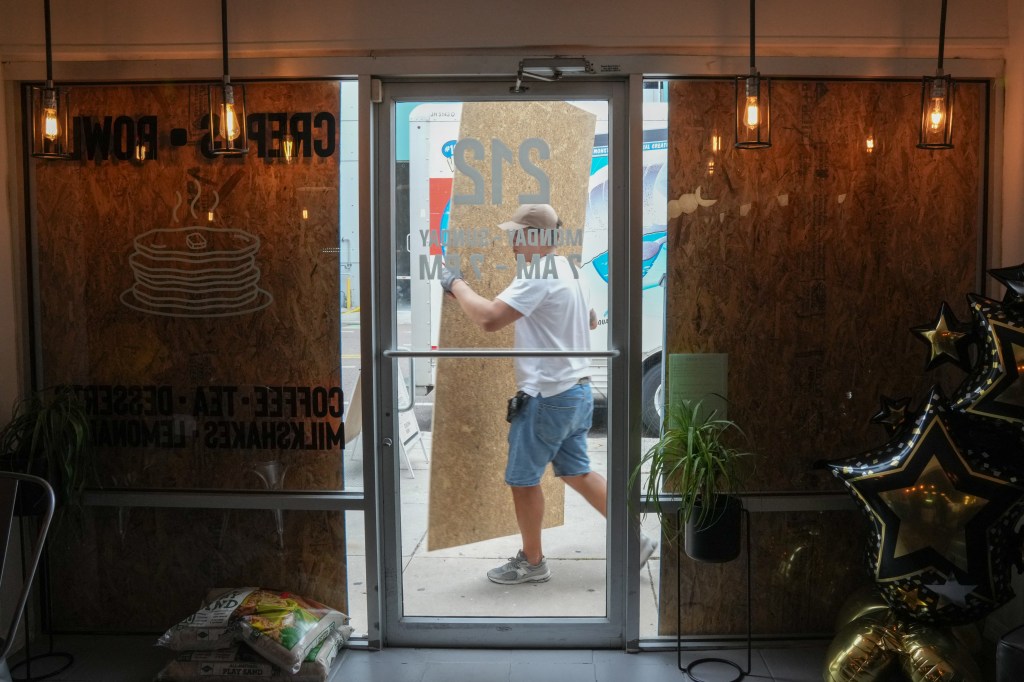 A man boarding up a cafe in Tampa in preparation for Milton's landfall.