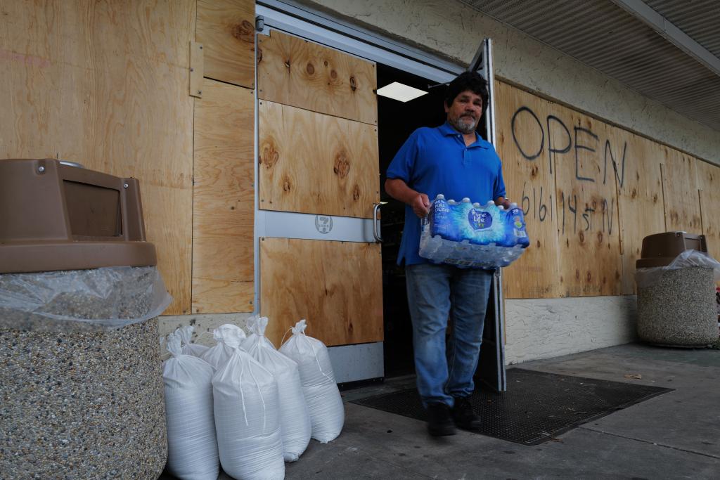 A man carrying bottled water out of a boarded up store in St. Petersburg in preparation for Milton on Oct. 8, 2024.