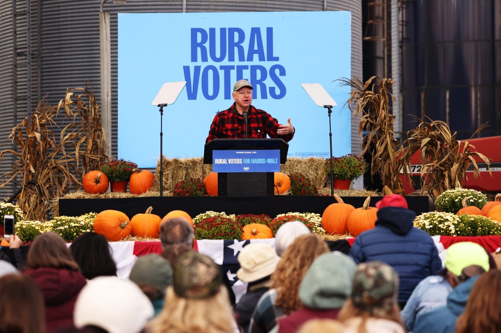 Tim Walz speaks at podium with "RURAL VOTERS" behind him and pumpkins all around.