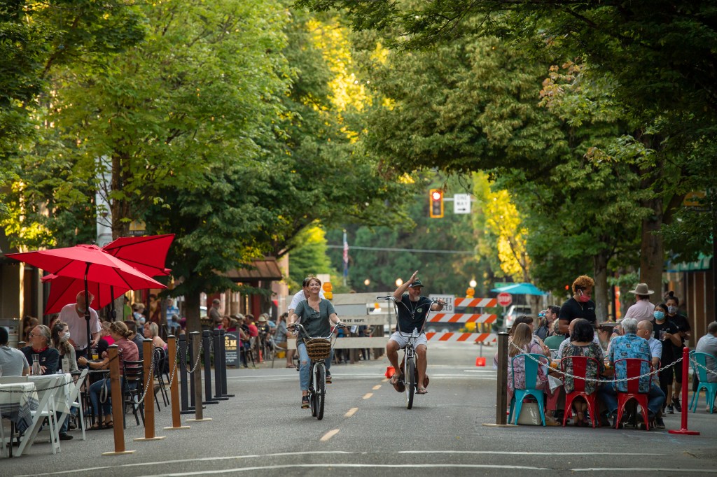 People riding bicycles on 3rd Street in McMinnville, Oregon, a destination known for biking and shopping