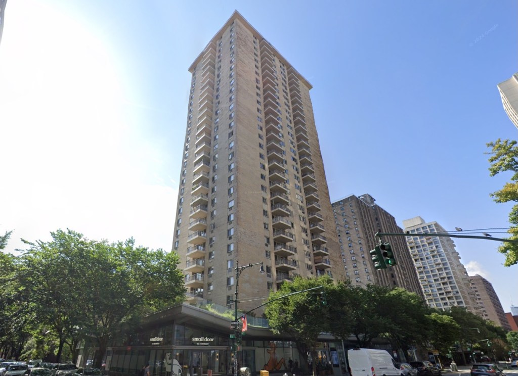 A tall building on 70 West 93rd Street, New York, NY with surrounding trees and a traffic light