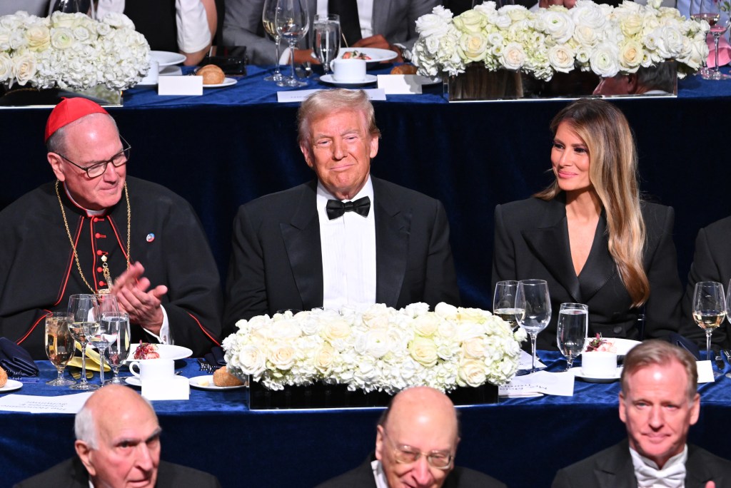 Donald Trump, Melania Trump, and other guests seated at a table at the 2024 Al Smith Memorial Foundation Dinner benefiting women and children in need.