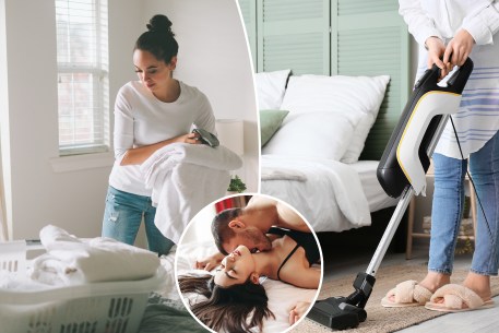 A woman folding laundry in a bright white bedroom